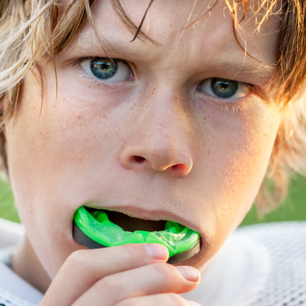 Young boy putting in his mouthguard while playing sports.