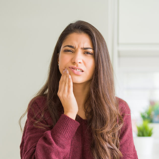 Young woman holding her jaw in pain.