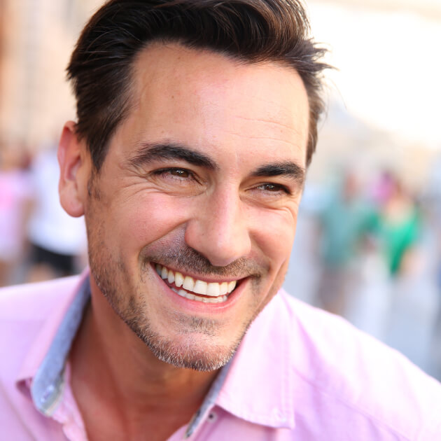 A gentleman in a pink shirt, smiling outside.