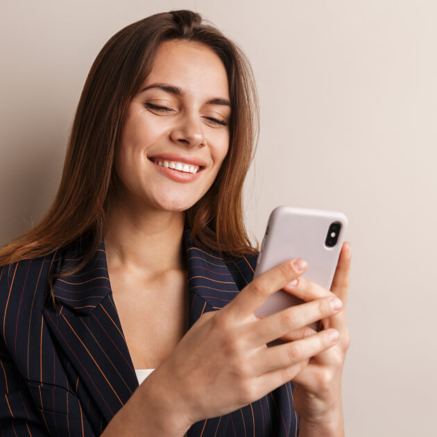 Young woman smiling and looking at her phone.